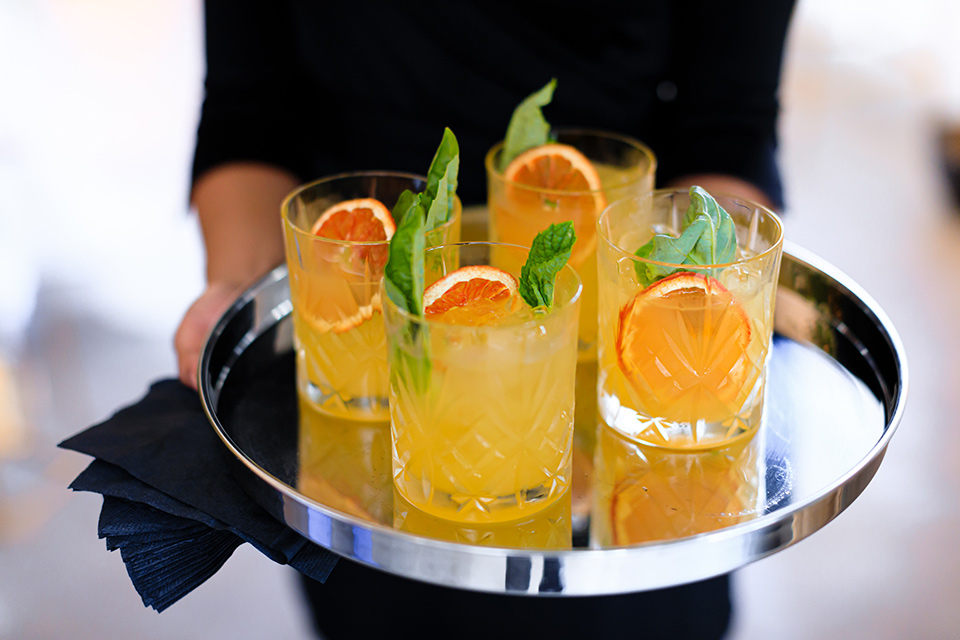 Yellow decorated cocktails with garnish and orange peel served on a platter