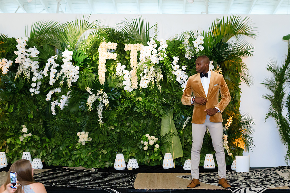 Friar Tux summer Bash model standing on velvet carpet in front of florals