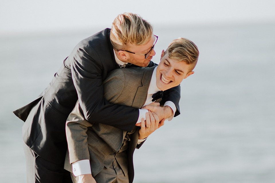 Sunset-Cliffs-Shoot-grooms-laughing-one-groom-in-a-grey-suit-with-the-other-groom-in-a-blue-suit