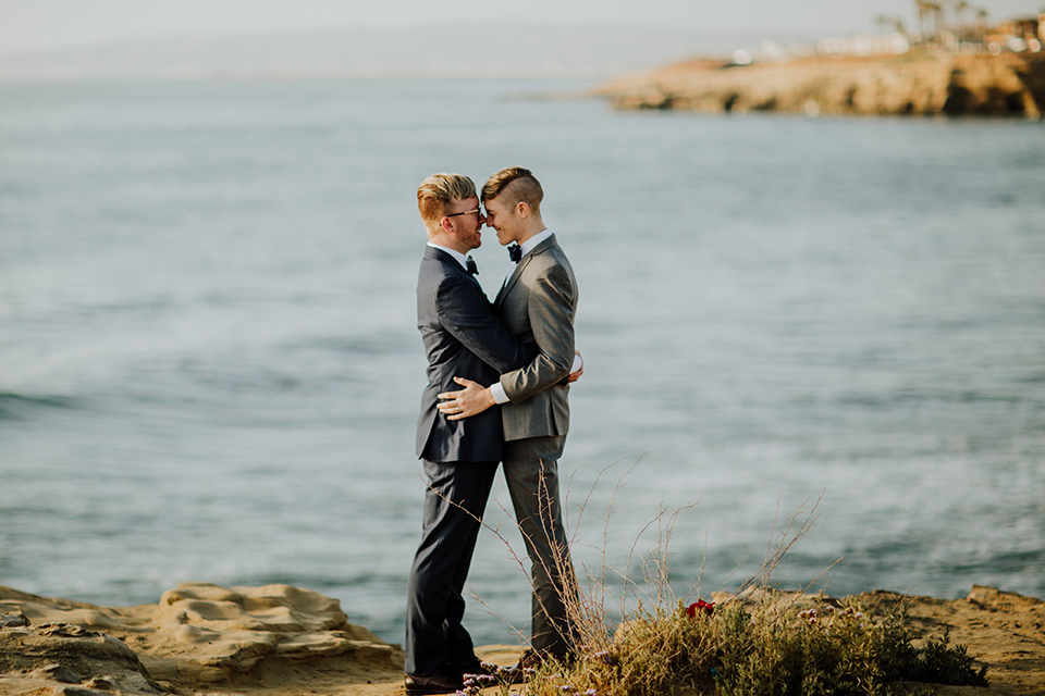 Sunset-Cliffs-Shoot-grooms-overlooking-ocean-one-groom-in-a-grey-suit-with-the-other-groom-in-a-blue-suit