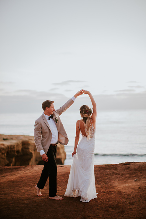 Sunset-Cliffs-Elopement-bride-and-groom-dancing-bride-in-a-lace-white-gown-with-thin-straps-groom-in-a-tan-suit-coat-with-black-pants-and-black-bow-tie