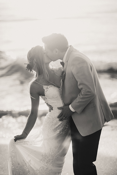 Sunset-Cliffs-Elopement-bride-and-groom-kissing-by-water-bride-in-a-lace-white-gown-with-thin-straps-groom-in-a-tan-suit-coat-with-black-pants-and-black-bow-tie