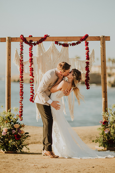 Sunset-Cliffs-Elopement-bride-and-groom-kiss-at-ceremony-bride-in-a-lace-white-gown-with-thin-straps-groom-in-a-tan-suit-coat-with-black-pants-and-black-bow-tie