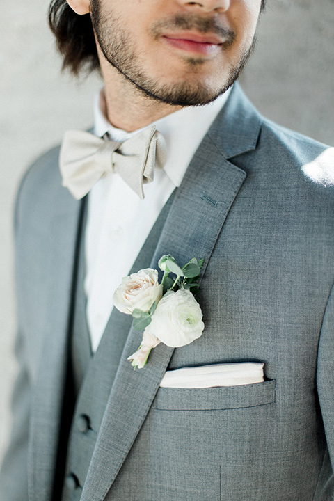 The-1912-Shoot-close-up-on-groom-suit-in-a-grey-suit-with-an-ivory-bow-tie