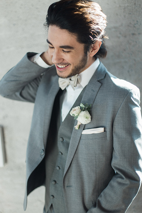 The-1912-Shoot-groom-laughing-in-a-grey-suit-with-a-white-bow-tie