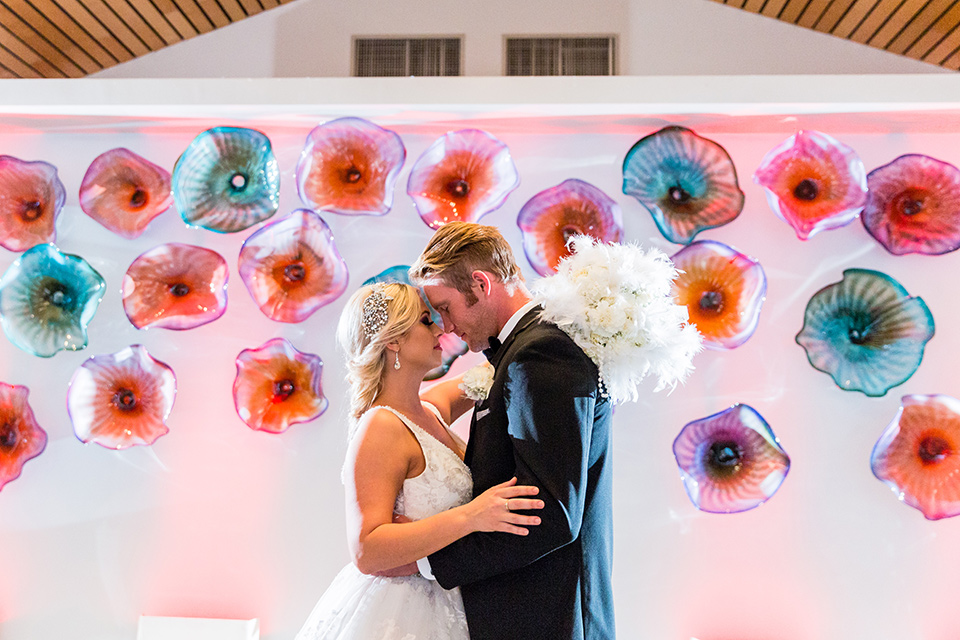 wedding bride and groom in front of pink flower art wall 