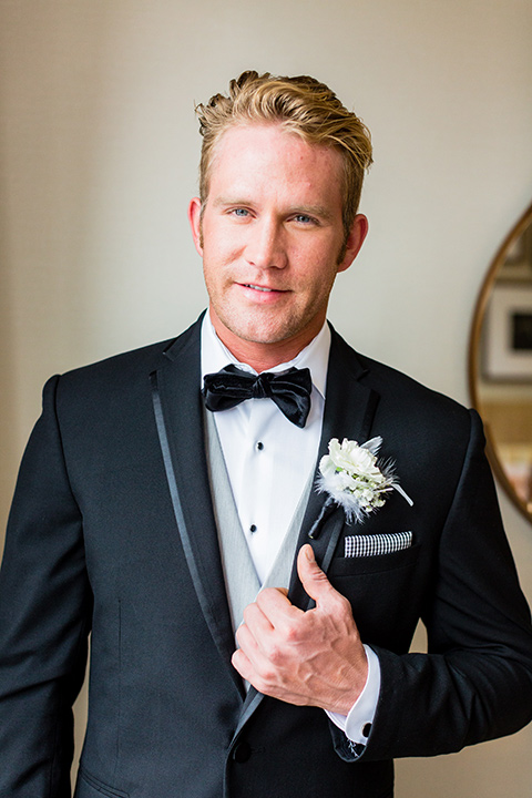 wedding groom holding jacket lapel in a black tuxedo jacket with a light grey pant and vest