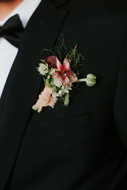 groom in a black suit with a long black tie close up