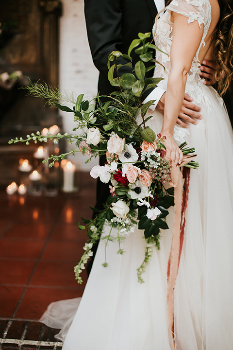 bride in a lace gown with a cap sleeve and illusion neckline and the groom in a black suit with a long black tie close up