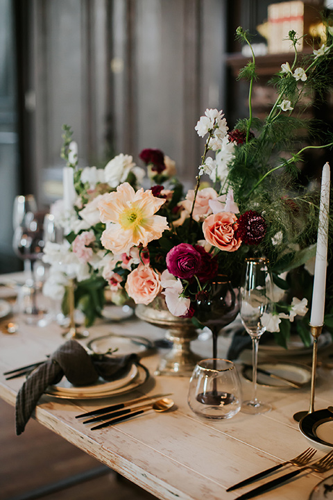 wooden tables with black candles and charger plates and white floral centerpiece