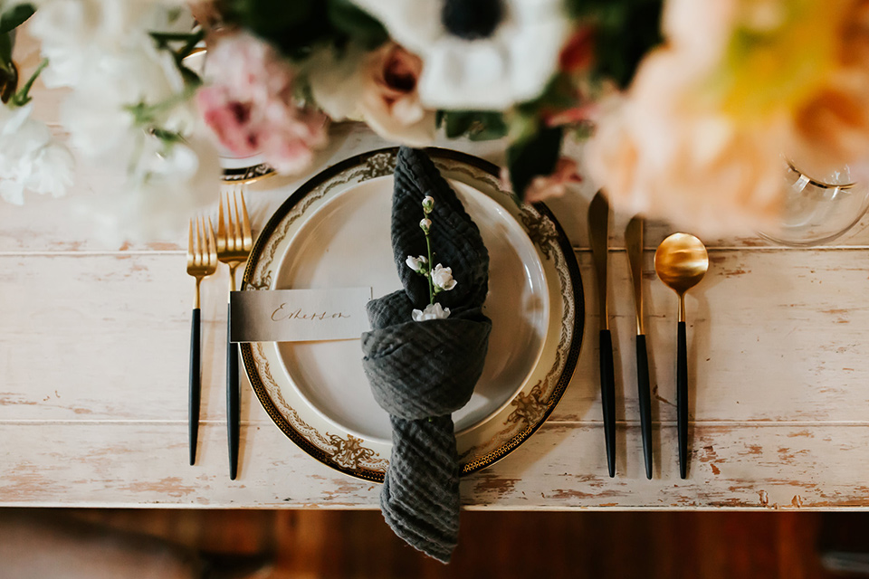 black table with white chairs and simple floral centerpiece design and white and black flatware