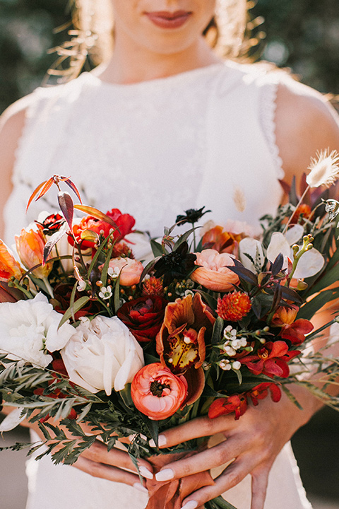 bride holding a fall inspired wedding bouquet with a white gown with a high neckline