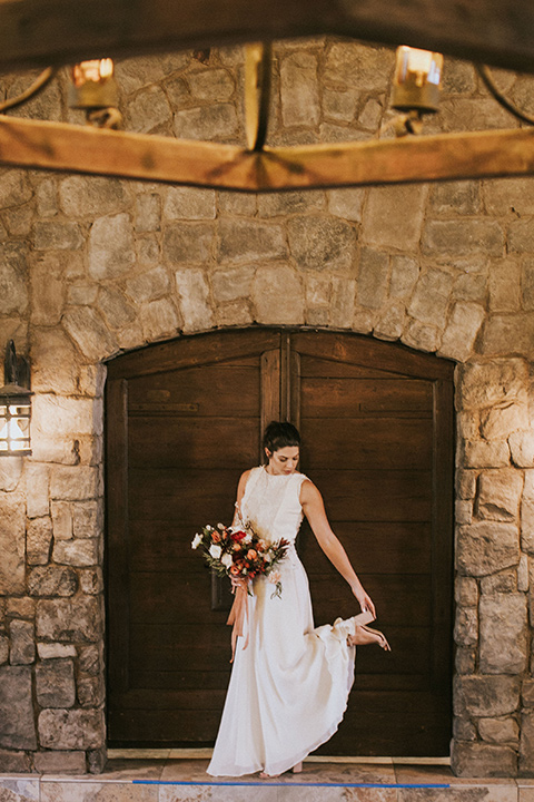 the bride in a white gown with a high neckline and sleeves, along with nude suede heels and her hair in a high ponytail