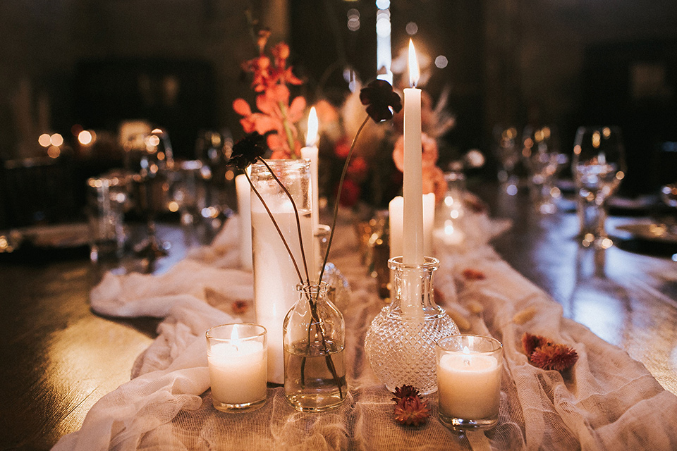 wooden table with white linens and tall candles and orange and white accents