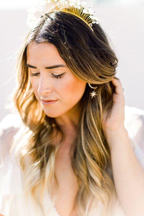 Bride in a cream and ivory flowing gown with a gold headband with stars with her hair in waves