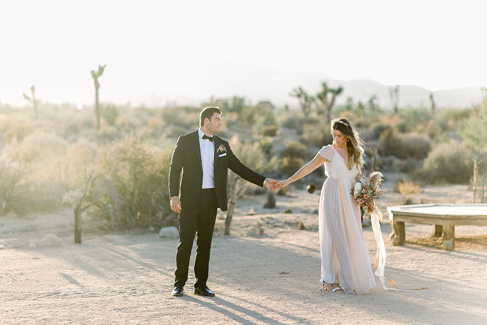 Bride in a cream and ivory flowing gown with a gold headband with stars and the groom in a black tuxedo with a black bow tie