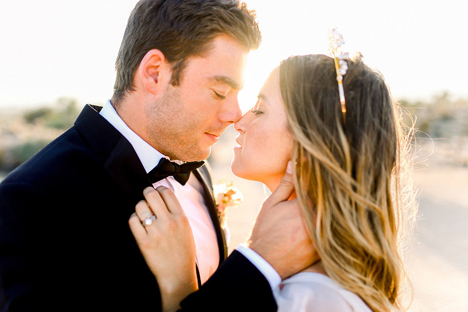 Bride in a cream and ivory flowing gown with a gold headband with stars and the groom in a black tuxedo with a black bow tie