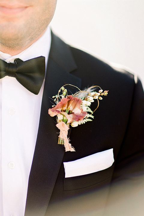 Black tuxedo with a black bow tie and a white and pink boutonnière