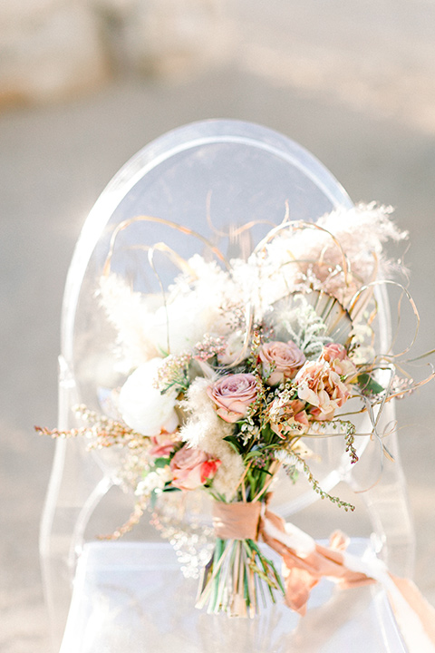 clear acrylic chairs with bridal bouquet on it with white and pink flowers