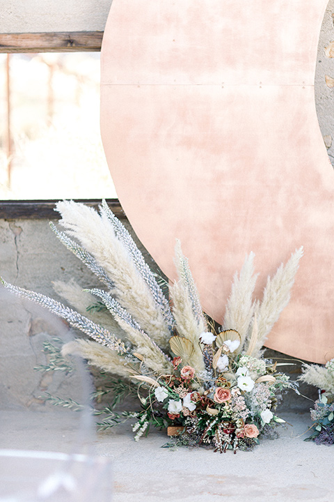 Rose gold moon ceremony décor and floral arrangements with pampas grass