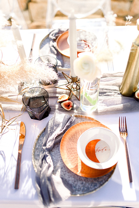  purple and silver table linens with tall white and gold candles with terracotta colored flatware 