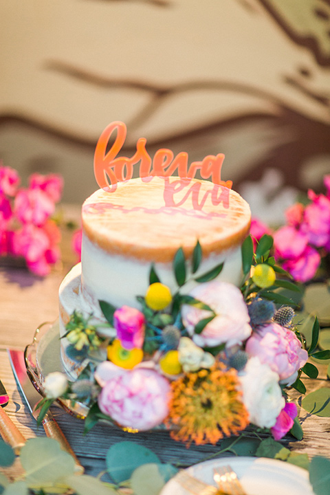 Topa-Winery-Wedding-cake-with-white-fondant-and-gold-trim-with-bright-florals-on-it