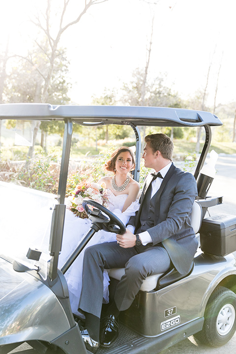 Vellano-Country-Club-bride-and-groom-in-golf-cart-bride-in-a-big-ballgown-with-her-hair-up-in-a-side-bun-groom-in-a-grey-tuxedo