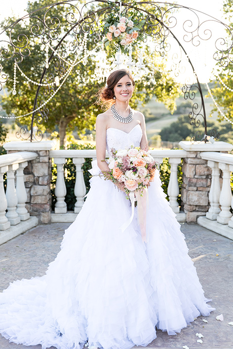 Vellano-Country-Club-bride-standing-holiding-flowers-in-a-big-strapless-ballgown