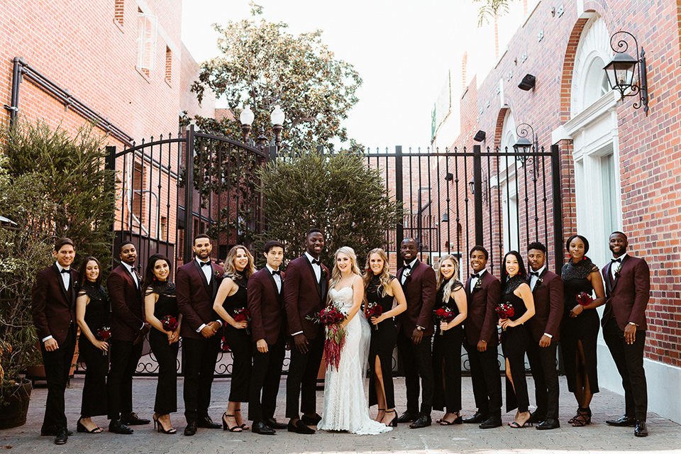 bridal party image with the groomsmen in burgundy tuxedos and bridesmaids in black dresses