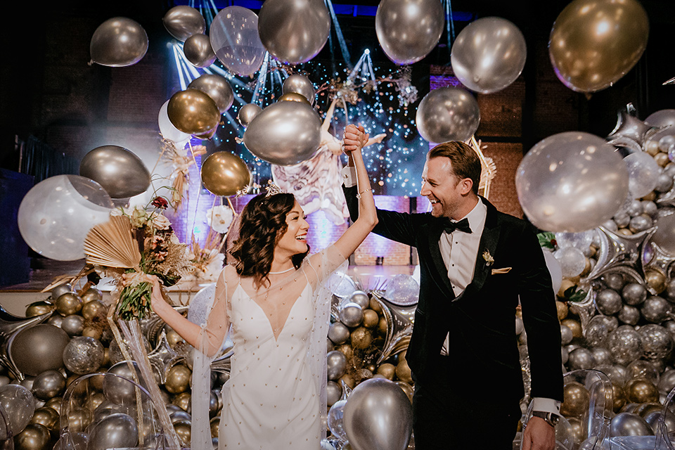 The-Yost-Theatre-bride-and-groom-with-balloons-bride-in-a-silk-modern-gown-with-star-accessories-and-groom-in-a-velvet-black-tuxedo