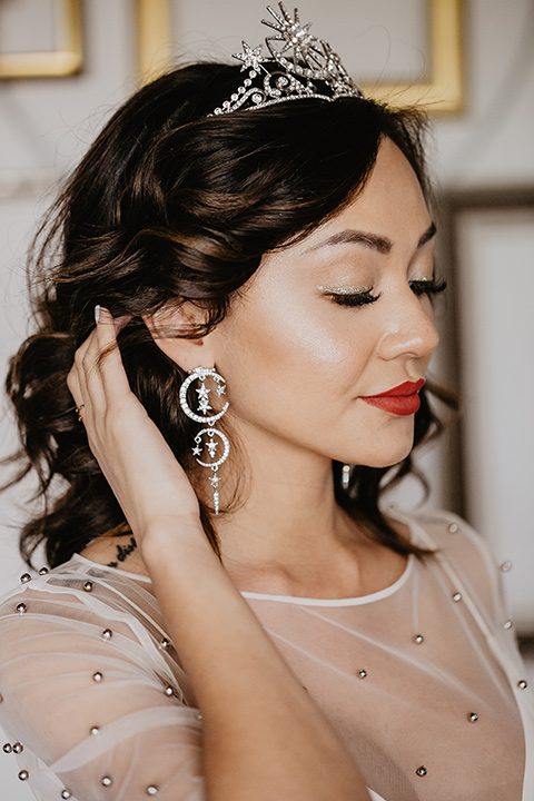 The-Yost-Theatre-bride-showing-off-earrings-design-bride-in-a-modern-silk-gown-with-a-sheer-beaded-overlay-and-star-inspired-jewelry