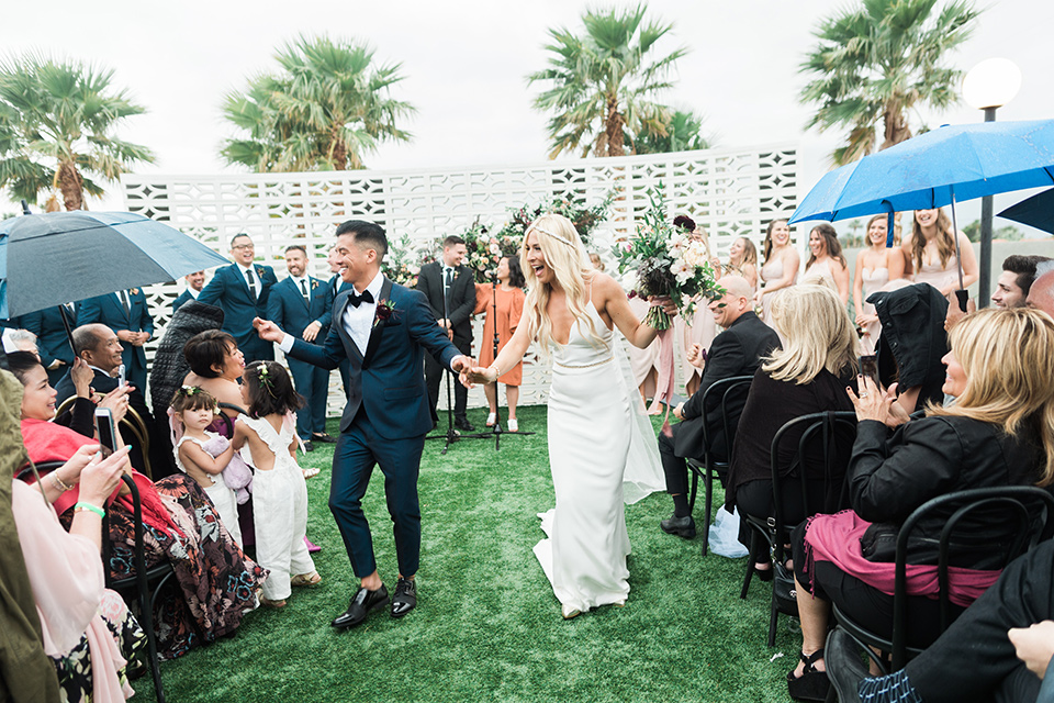 the-lautner-compound-wedding-bride-and-groom-ceremony-walk-the-bride-wore-a-lace-fitted-gown-and-groom-in-a-bue-shawl-lapel-tuxedo