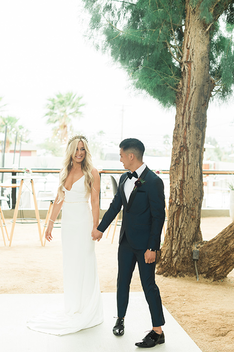 the-lautner-compound-wedding-bride-and-groom-first-look-one-bride-in-a-lace-formfitting-gown-groom-in-a-navy-shawl-lapel-tuxedo