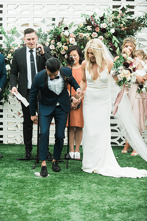 the-lautner-compound-wedding-bride-and-groom-stomp-on-glass-bride-in-a-lace-formfitting-gown-groom-in-a-navy-shawl-lapel-tuxedo