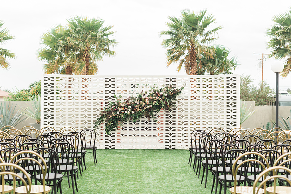 the-lautner-compound-wedding-ceremony-space-with-with-black-chairs-and-white-archway-decor