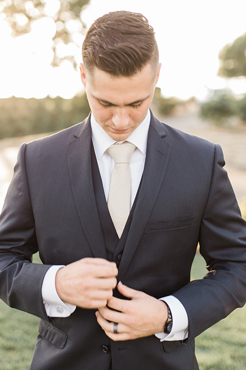 Temecula-outdoor-wedding-at-callaway-winery-groom-navy-suit-buttoning-jacket