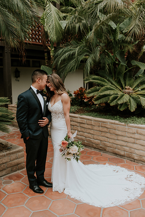 la-jola-shores-hotel-wedding-bride-and-groom-touching-heads-bride-in-a-satin-gown-with-a-silver-bodice-and-straps-groom-in-a-navy-tuxedo-and-black-bow-tie
