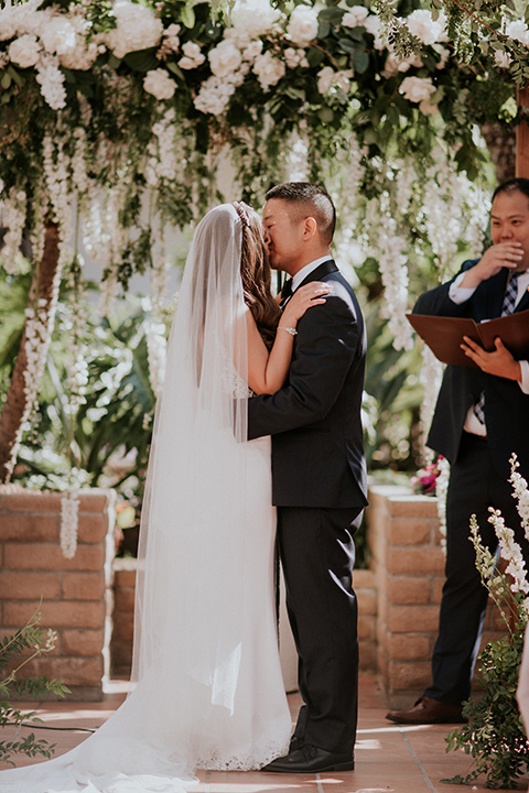 la-jola-shores-hotel-wedding-first-kiss-bride-in-a-silk-fitted-gown-with-straps-groom-in-a-dark-blue-tuxedo