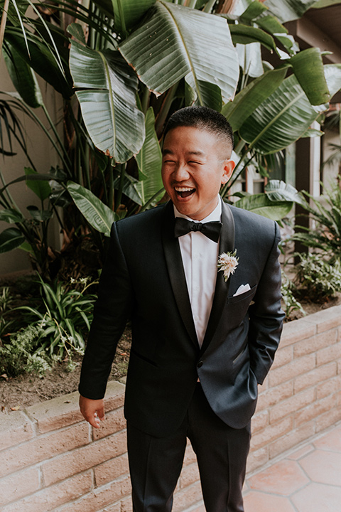 la-jola-shores-hotel-wedding-groom-laughing-in-a-navy-shawl-lapel-tuxedo-and-black-bow-tie