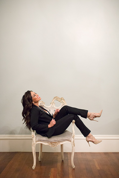 female-tuxedo-sitting-in-a-chair-in-a-shawl-lapel-black-tuxedo-and-nude-high-heels