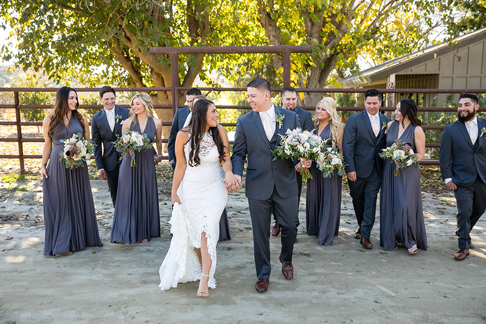 gallway-downs-wedding-bridal-party-walking-bridesmaids-in-a-mauve-purple-color-and-groomsmen-in-a-charcoal-suit-with-the-bride-in-a-lace-form-fitting-gown-with-a-high-neckline-and-keyhole-back-groom-in-a-charcoal-tux-withan-ivory-long-tie