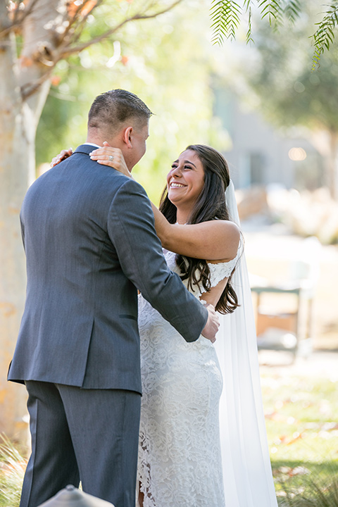 gallway-downs-wedding-bride-and-groom-first-look-bride-in-a-lace-dress-with-a-high-slit-and-a-high-neckline-groom-in-a-dark-grey-suit