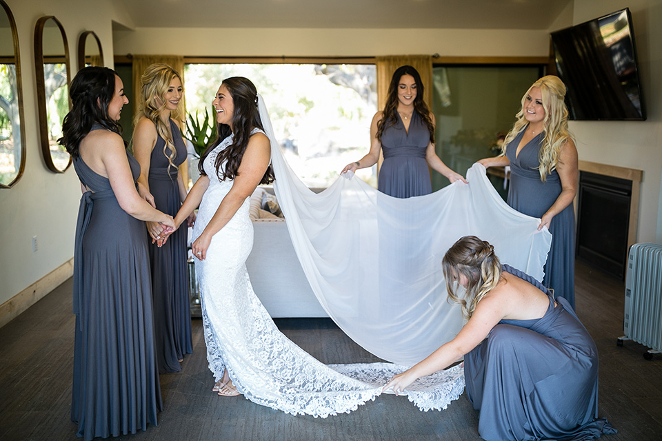 gallway-downs-wedding-bride-and-her-bridesmaids-helping-her-get-ready-bridesmaids-in-a-mauve-purple-color-the-bride-in-a-lace-form-fitting-gown-with-a-high-neckline-and-keyhole-back-groom-in-a-charcoal-tux-withan-ivory-long-tie