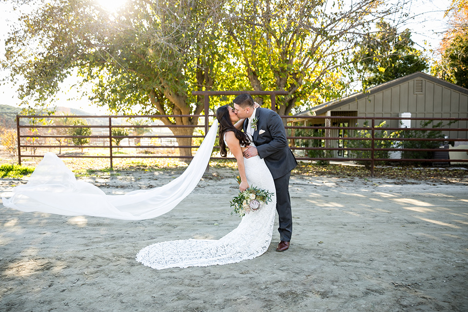 gallway-downs-wedding-groom-dipping-bride-with-her-veil-flowing-bride-in-a-lace-form-fitting-gown-with-a-high-neckline-and-keyhole-back-groom-in-a-charcoal-tux-withan-ivory-long-tie-groom-in-a-charcoal-grey-tuxedo-with-a-blush-tie