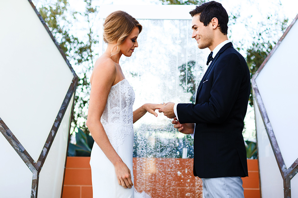 Intercontinental-DTLA-shoot-exchanging-rings-bride-wearing-a-stapless-white-gown-with-lace-detail-and-the-groom-wearing-a-two-toned-tuxedo-in-black-and-grey