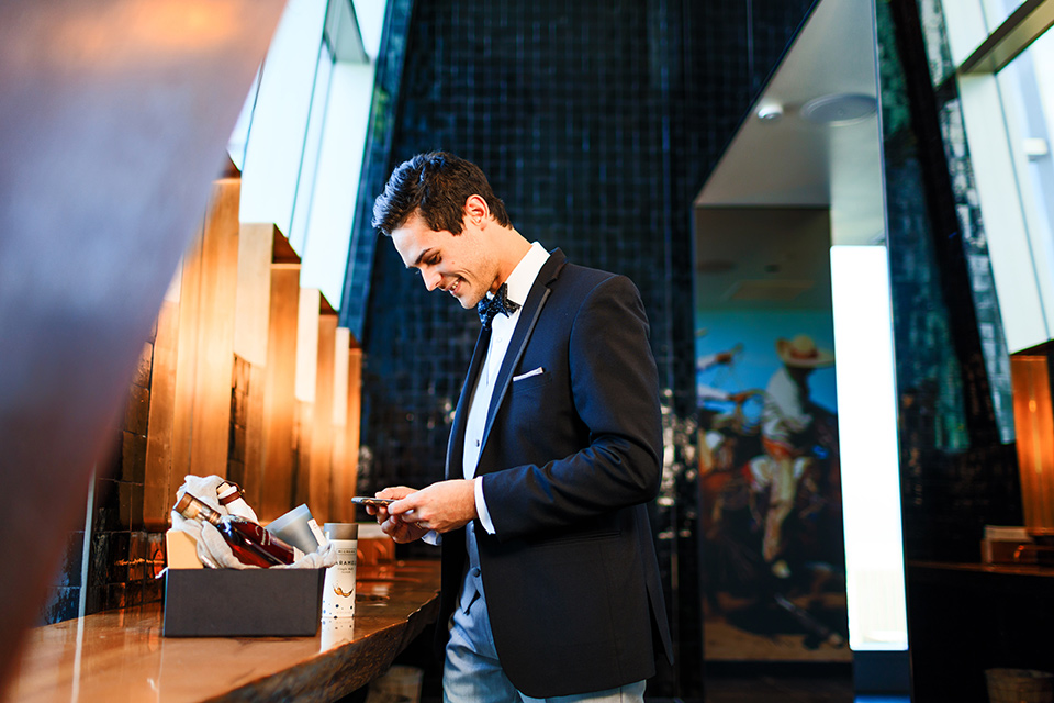 Intercontinental-DTLA-shoot-groom-looking-at-gift-basket-groom-wearing-a-two-toned-tuxedo-in-black-and-grey