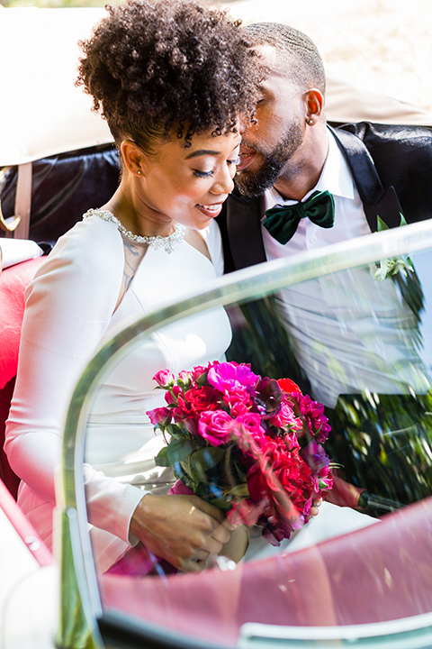 muckenthaler-mansion-bride-and-groom-driving-in-car-bride-looking-at-camera-in-a-satin-gown-with-an-illusion-back-and-groom-in-a-black-velet-tux