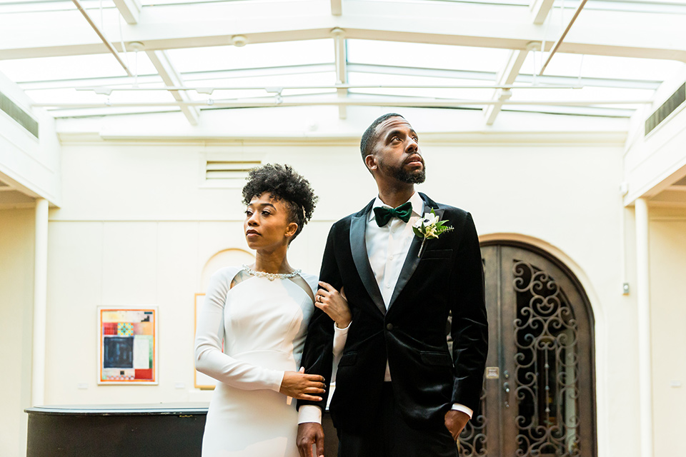 muckenthaler-mansion-bride-and-groom-looking-away-from-each-other-bride-in-a-vintage-satin-gown-and-groom-in-a-velvet-tuxedo-with-a-green-velvet-bow-tie