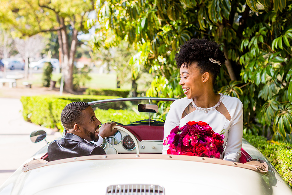 muckenthaler-mansion-couple-driving-away-bride-in-a-vintage-satin-gown-and-groom-in-a-velvet-tuxedo-with-a-green-velvet-bow-tie