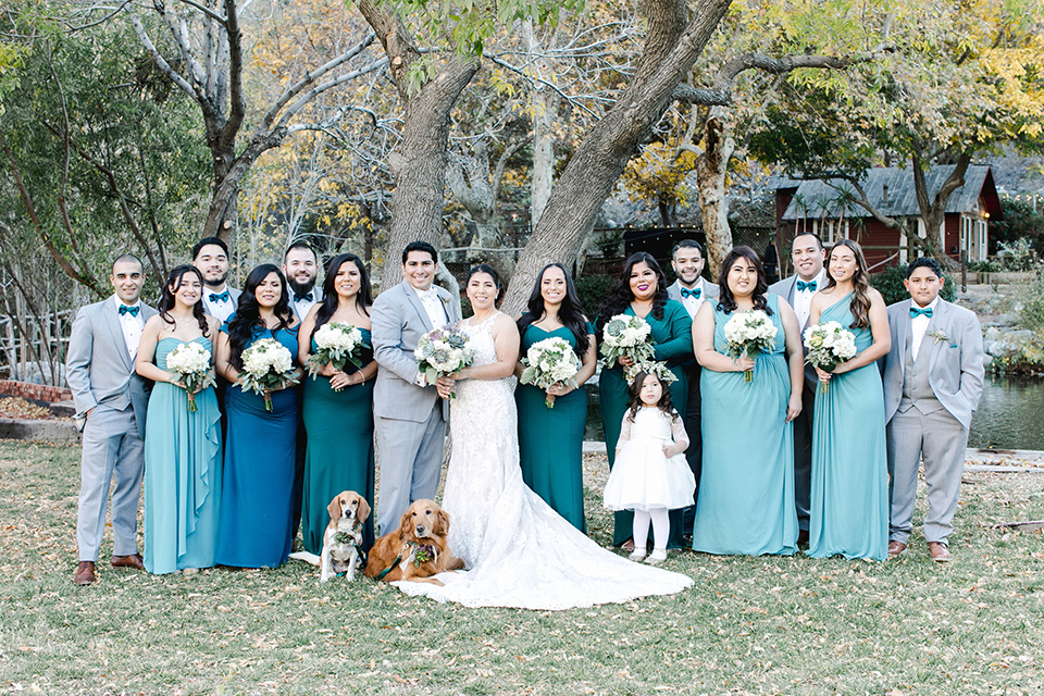 hidden-acres-wedding-bridal-party-bridesmaids-in-blue-dresses-groomsmen-in-grey-suits-and-blue-bow-ties-bride-in-fitted-gown-with-an-illusion-neckline-and-groom-in-a-grey-suit-with-a-white-bow-tie